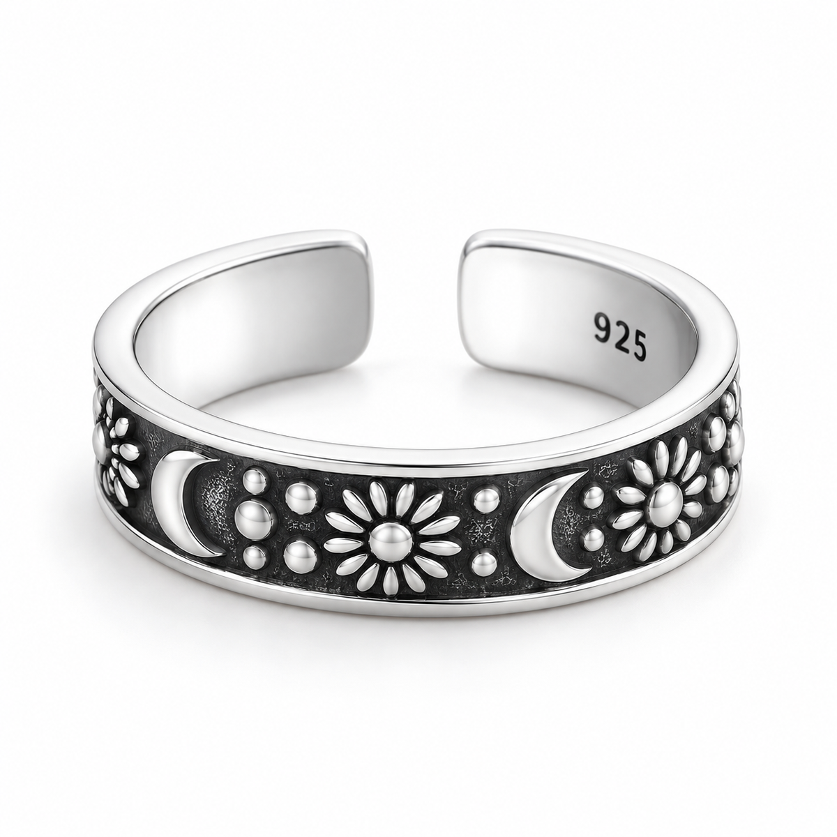 Open sterling silver ring with raised crescent moons, sunbursts and dots on a dark recessed band